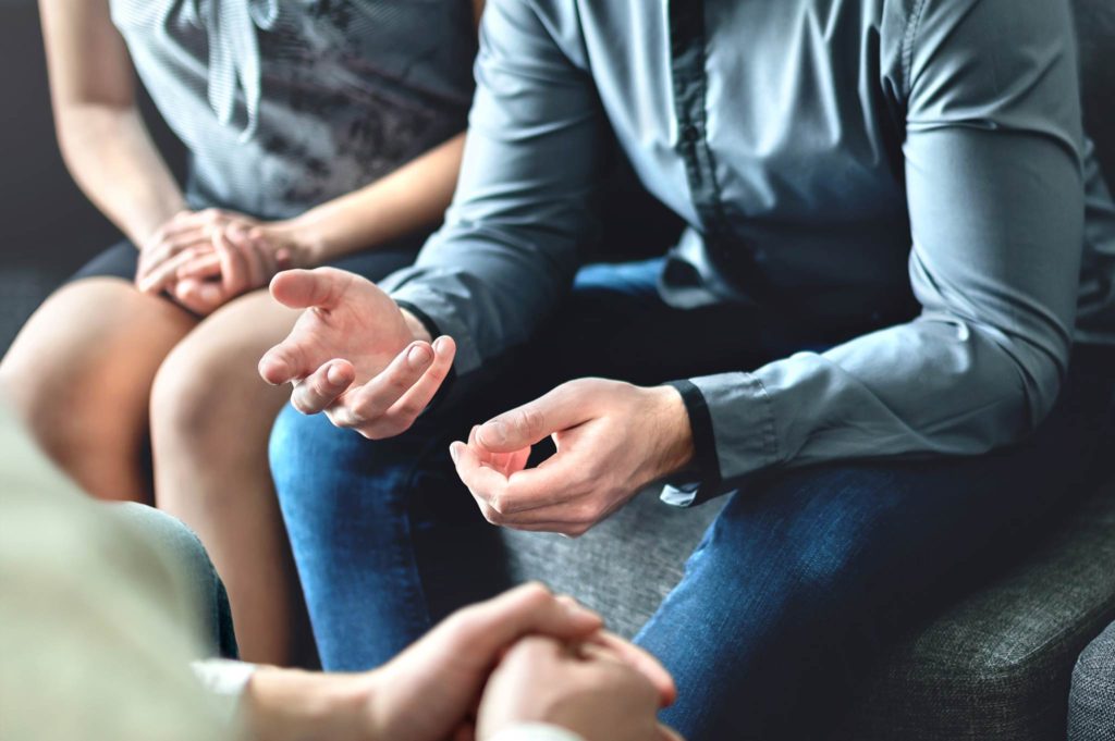 Close-up of gesturing hands during a family mediation session.
