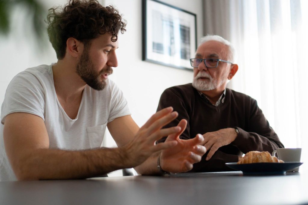 Man speaking and gesturing to his father during a family mediation session
